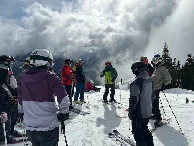 Trainer on-snow with trainees learning about adaptive skiing/snowboarding