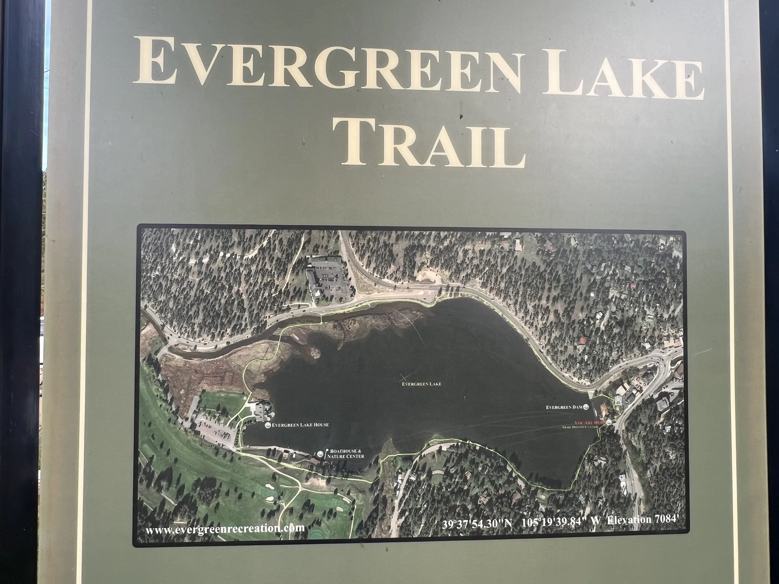 Signboard for Evergreen Lake Trail showing a map of the trail around Evergreen Lake, including points like Evergreen Lake House, Boathouse and Nature Center, and several trail paths. Coordinates and website URL are also displayed.