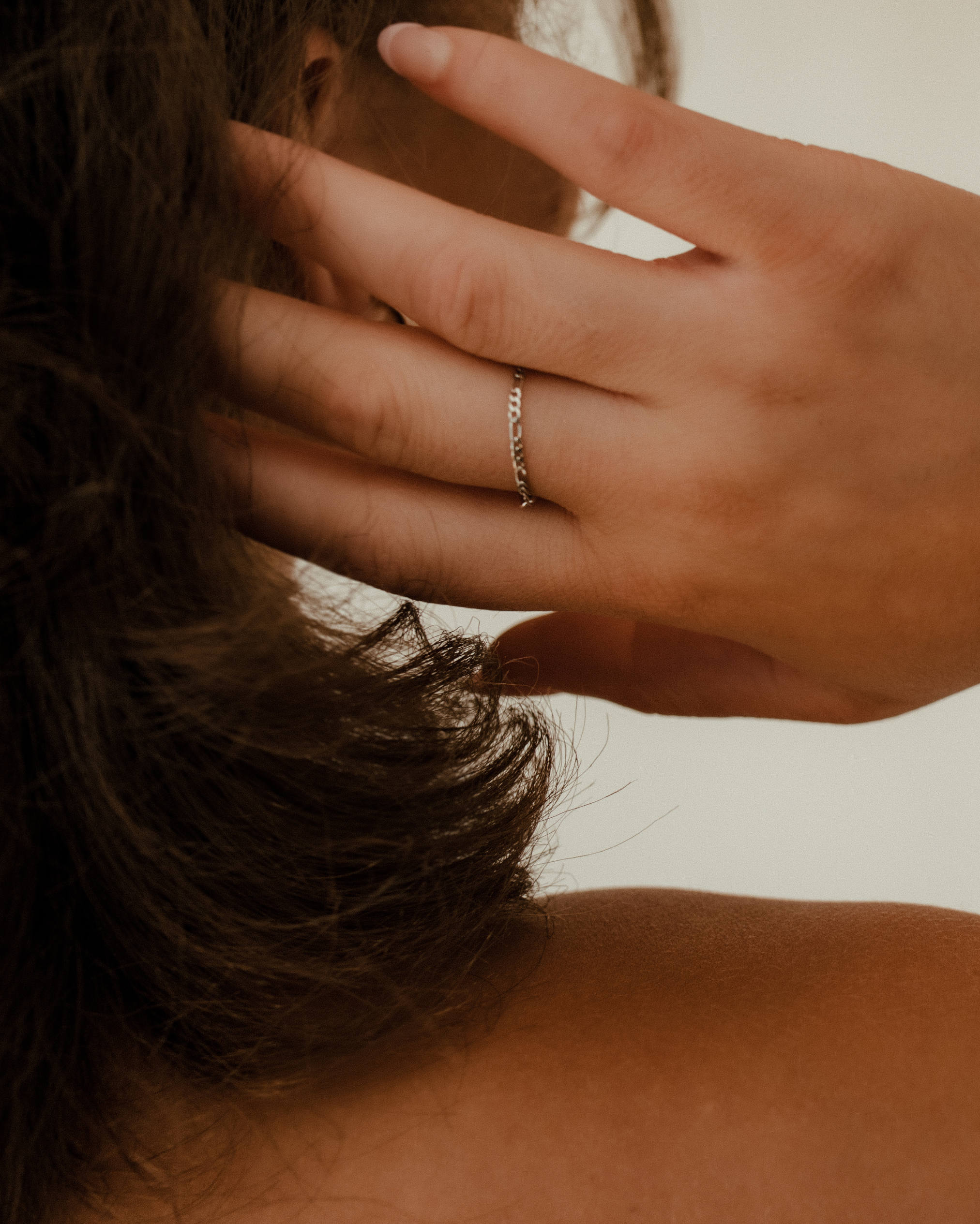 permanent jewelry ring on hand that is going into brunette hair