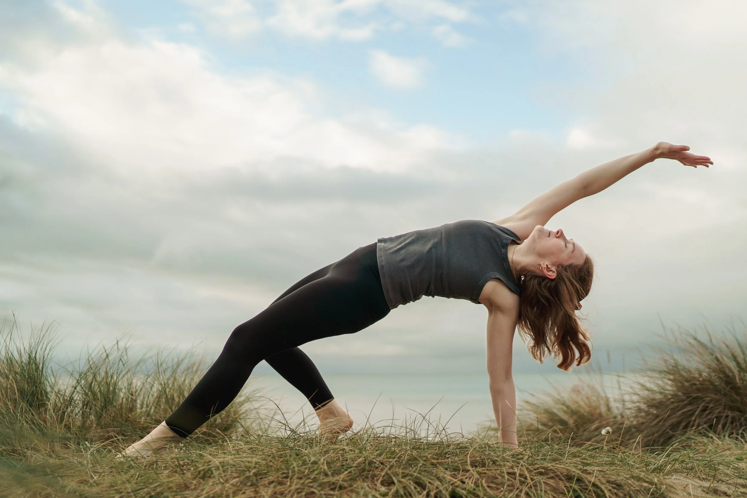 Woman practicing yoga outdoors on grassy field
