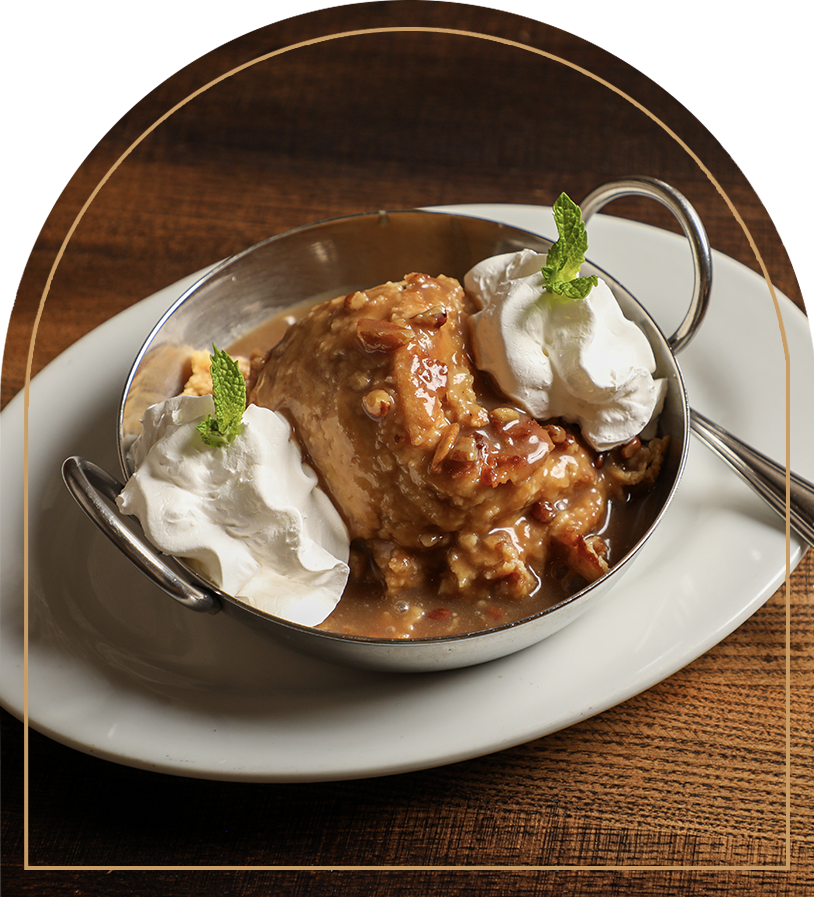 Pie with whipped cream and mint leaves in a metal dish on a white plate.
