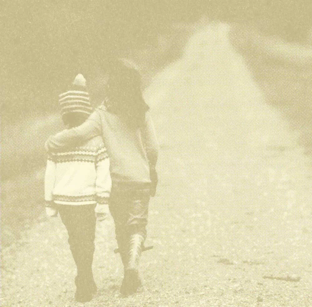 Two children walking outdoors along a dirt path in a rural setting.