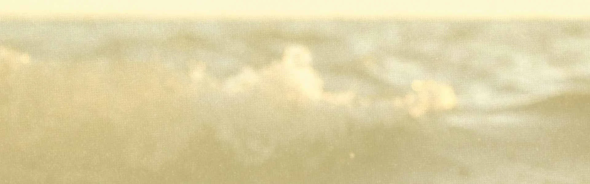 A mostly cloudy sky with a faint sun or moon and a yellowish tint.