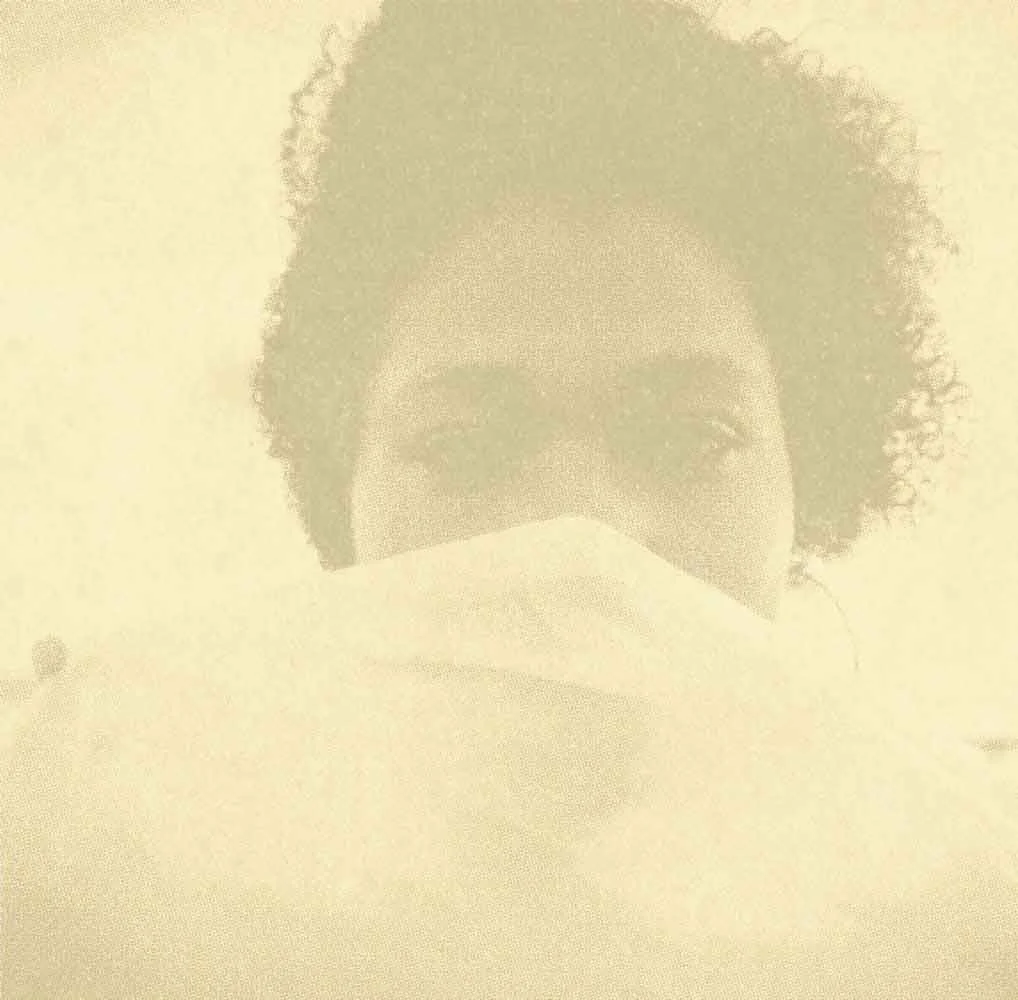 Person with curly hair wearing a face mask.