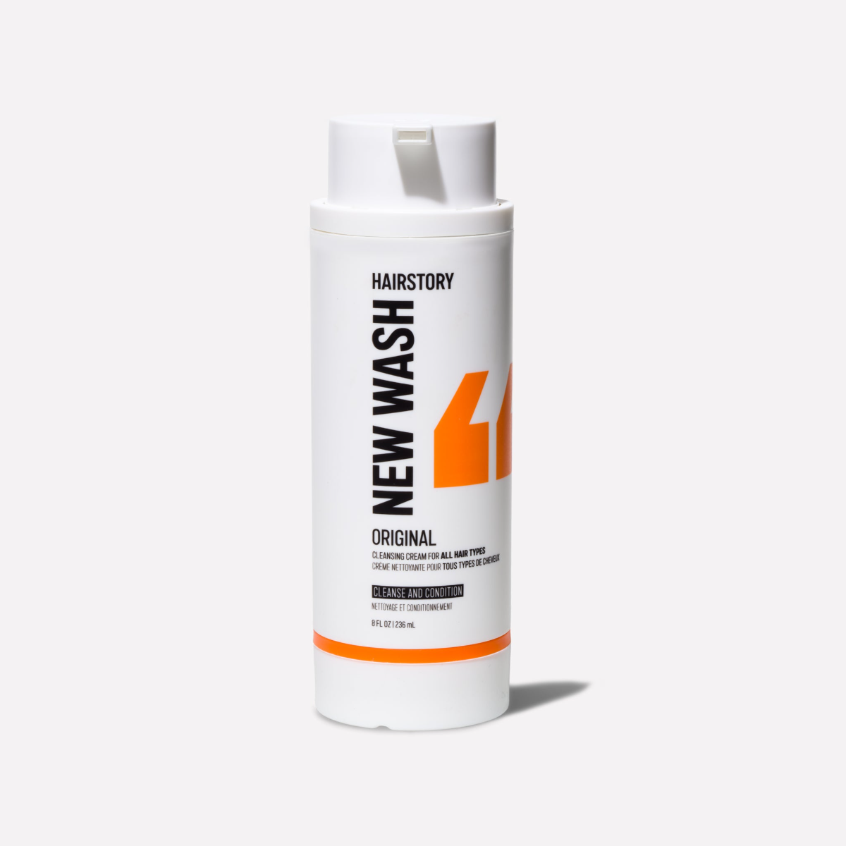 Image of a new wash shampoo bottle. Orange quotation marks and black text on a white bottle.