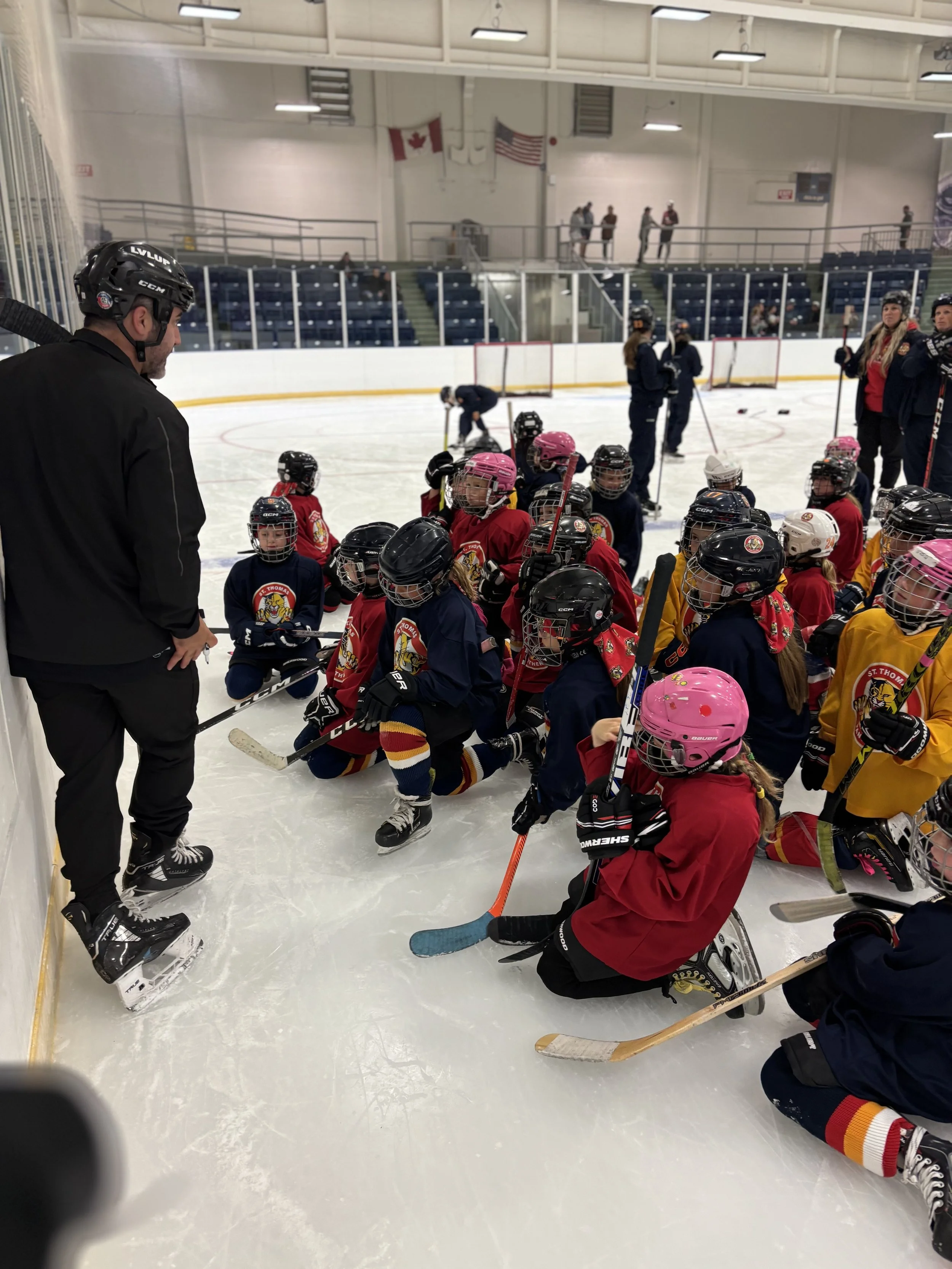 Hockey coach giving instructions to young hockey players on the ice rink during practice or game.