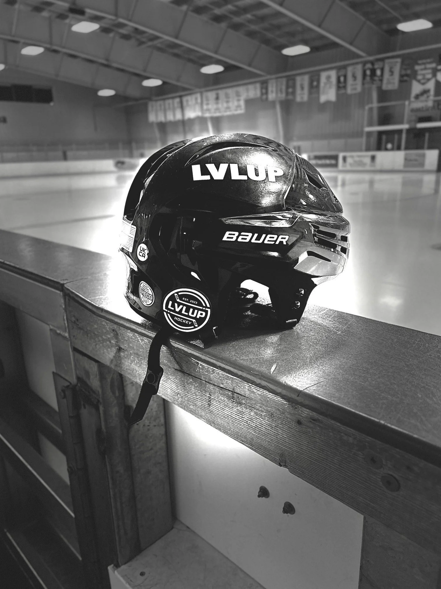 Hockey helmet resting on a rink's edge with an ice hockey rink in the background.