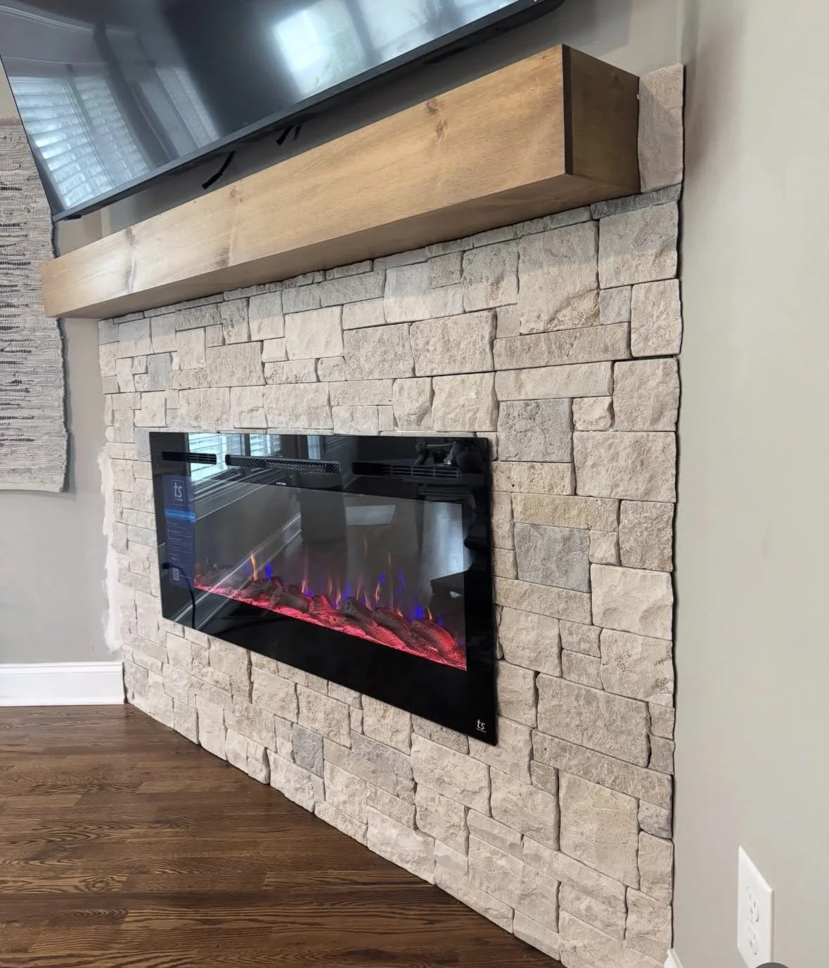 Custom Fireplace installation - Stone veneer finish. 
Stone veneer surround with electric fireplace installation and a custom mantel for a clean, high-end look.