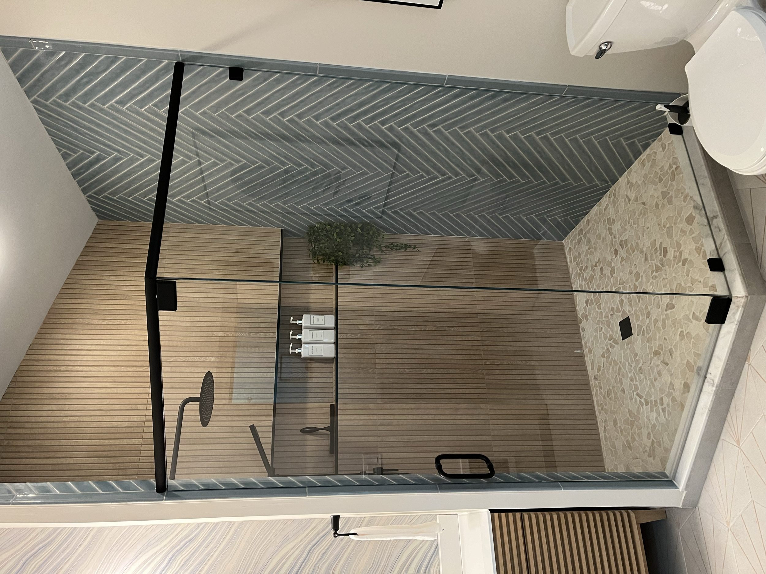 Master bathroom update-Walk-in Shower.
New walk-in shower featuring wood-look tile, herringbone detail, custom glass enclosure, and sleek black fixtures. 