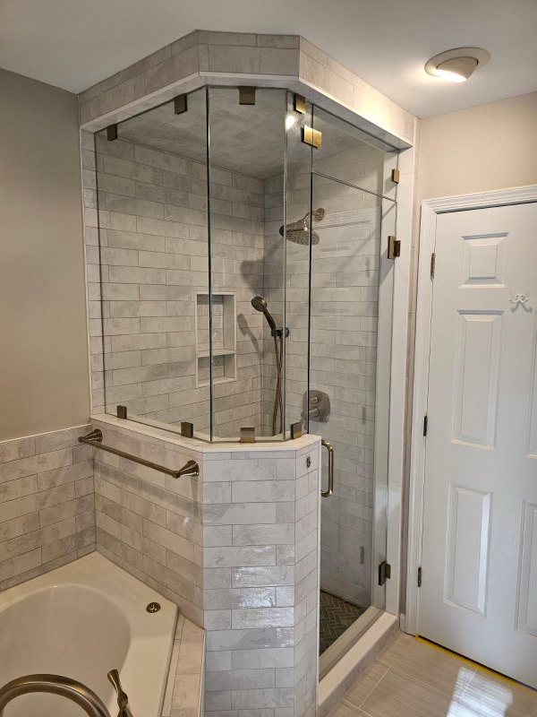 Custom steam shower installation- Custom niche and bench with sloped ceiling for proper steam drainage, finished with custom glass door and gold fixtures.