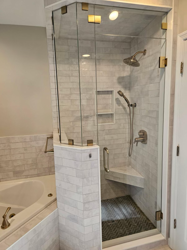 Custom steam shower installation- Custom niche and bench with sloped ceiling for proper steam drainage, finished with custom glass door and gold fixtures.