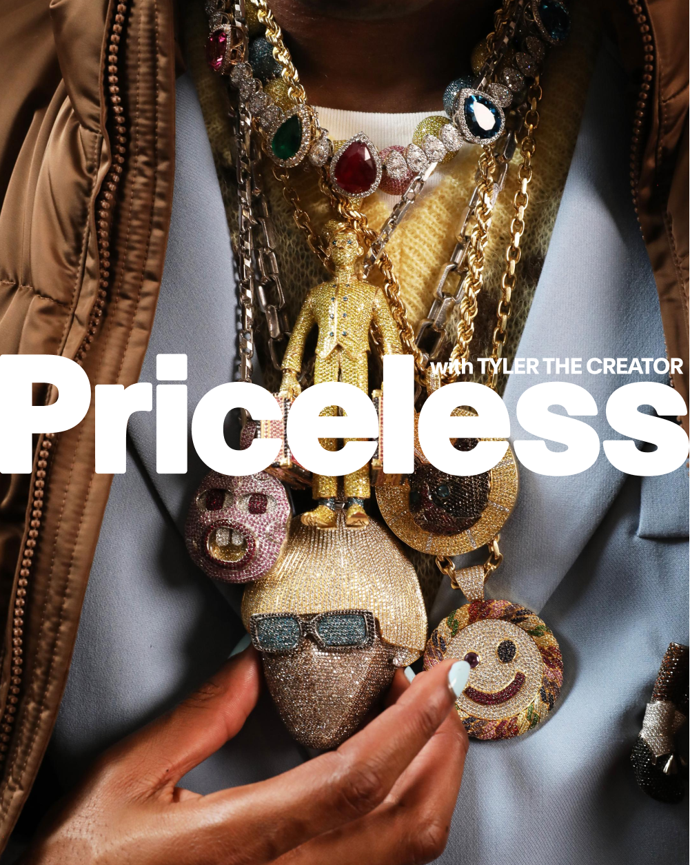 Close-up of a person wearing multiple colorful, jeweled necklaces and large, decorative brooches, including a smiling face, skull, and sunglasses, with a brown jacket and gray shirt.