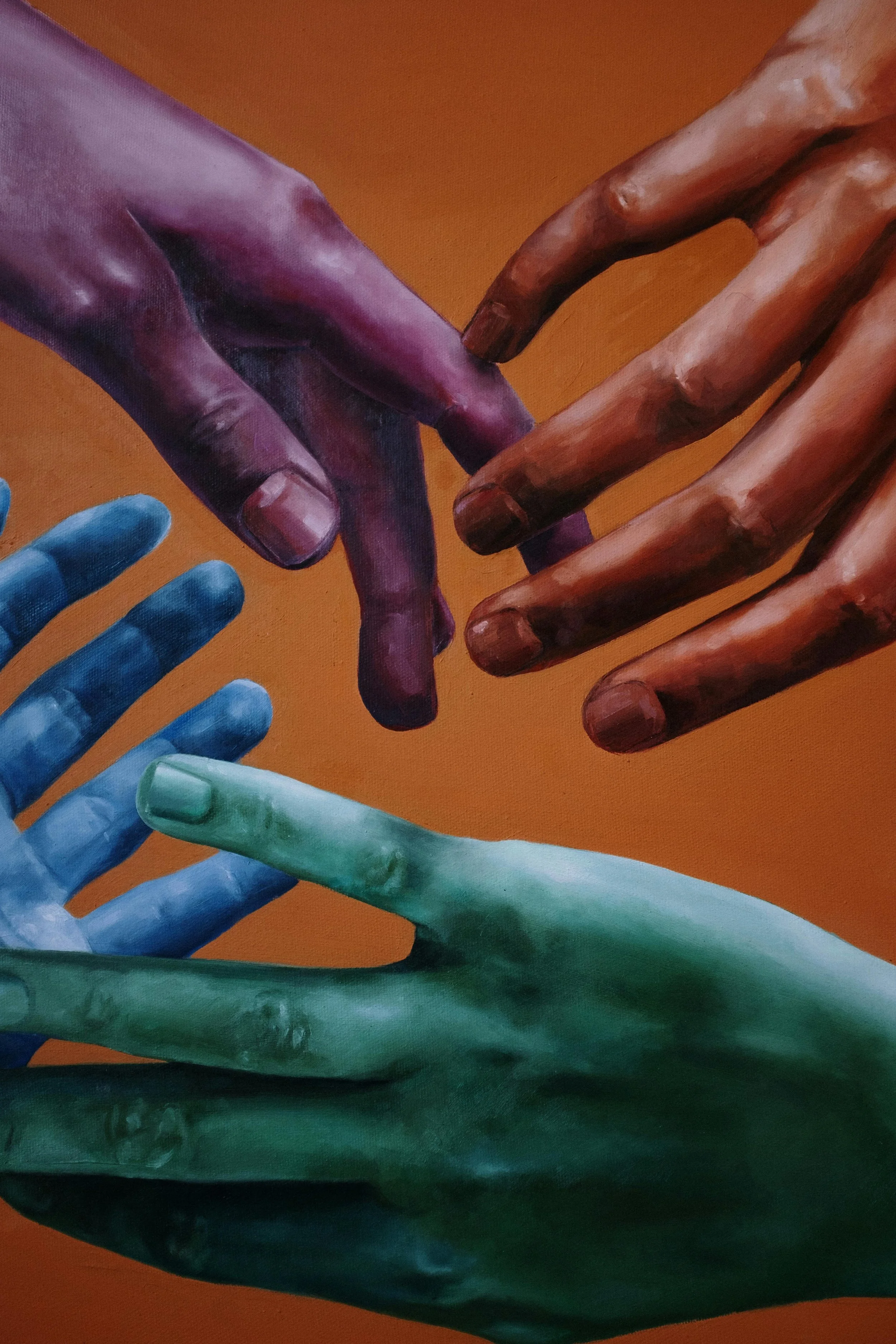 Painting of hands in various colors, reaching out towards each other against an orange background.