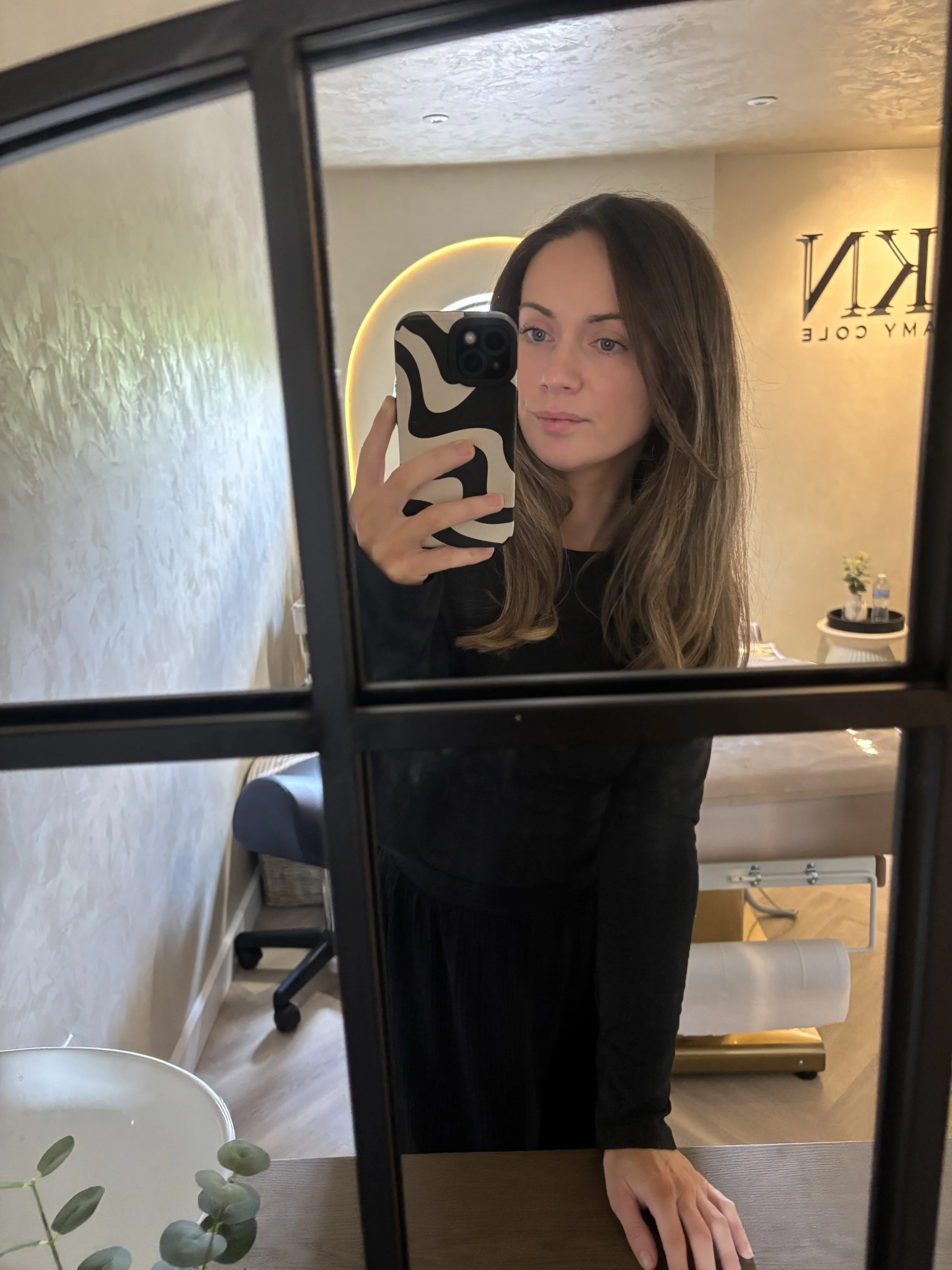 A woman taking a mirror selfie in a room.