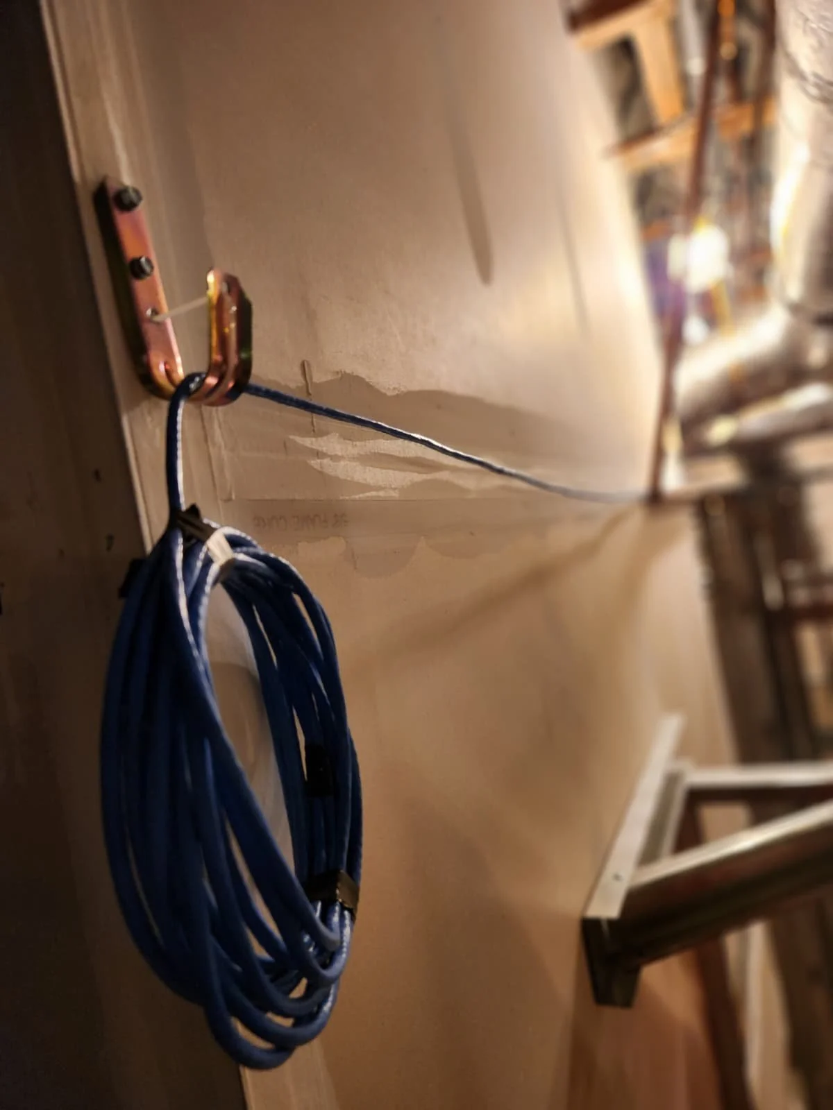 A copper coil with a blue wire attached, mounted on a wooden surface in a workshop.