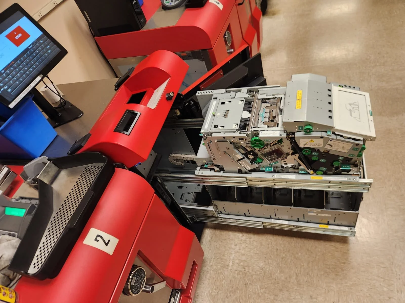 An open cash register with its electronic components exposed, placed on a checkout counter in a retail store.