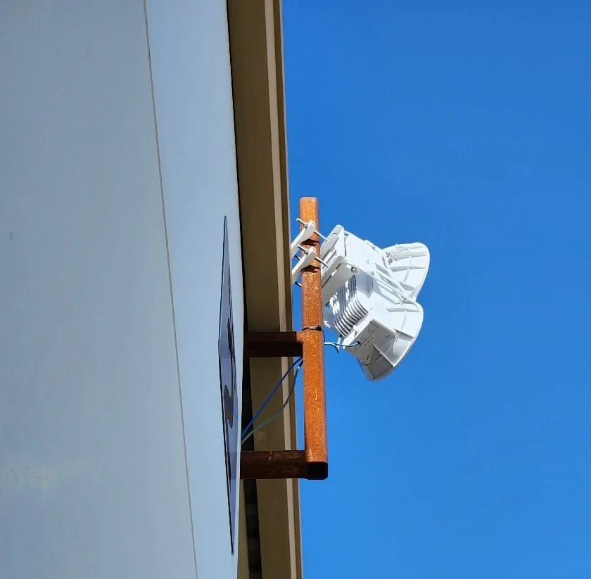Television or radio antenna mounted on a building rooftop against a clear blue sky.