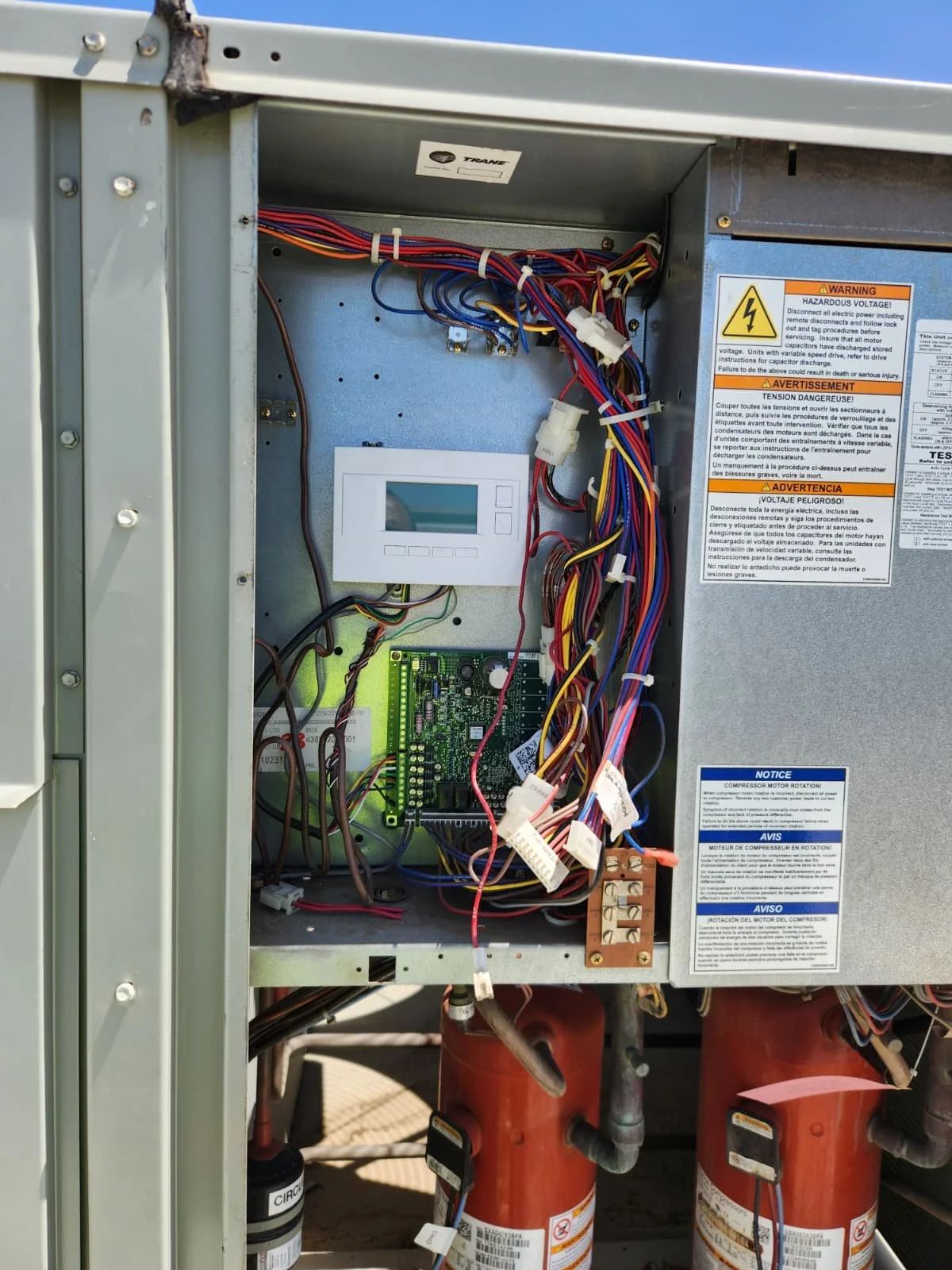 Open electrical panel with various wires, circuit board, digital display, and warning labels.