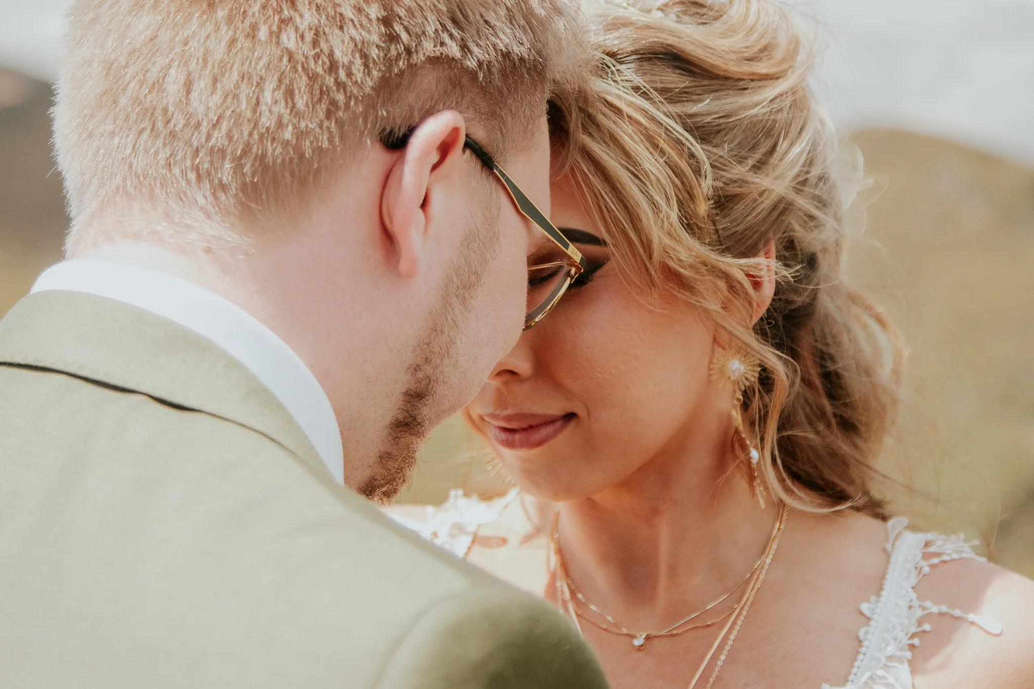 A close-up of a couple with foreheads touching and eyes closed, smiling softly.