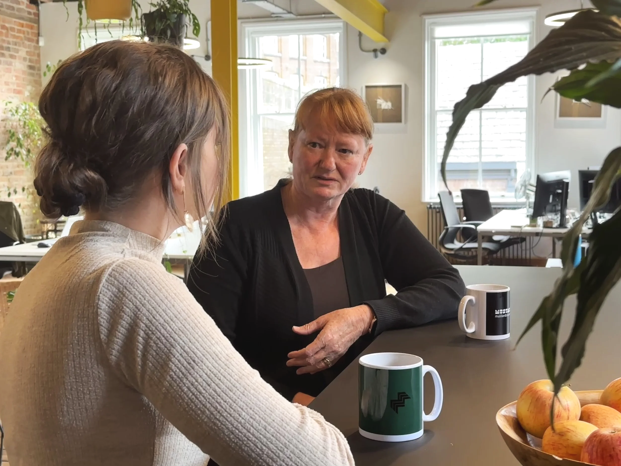 Jac speaking with professional woman at a bench with coffee cups
