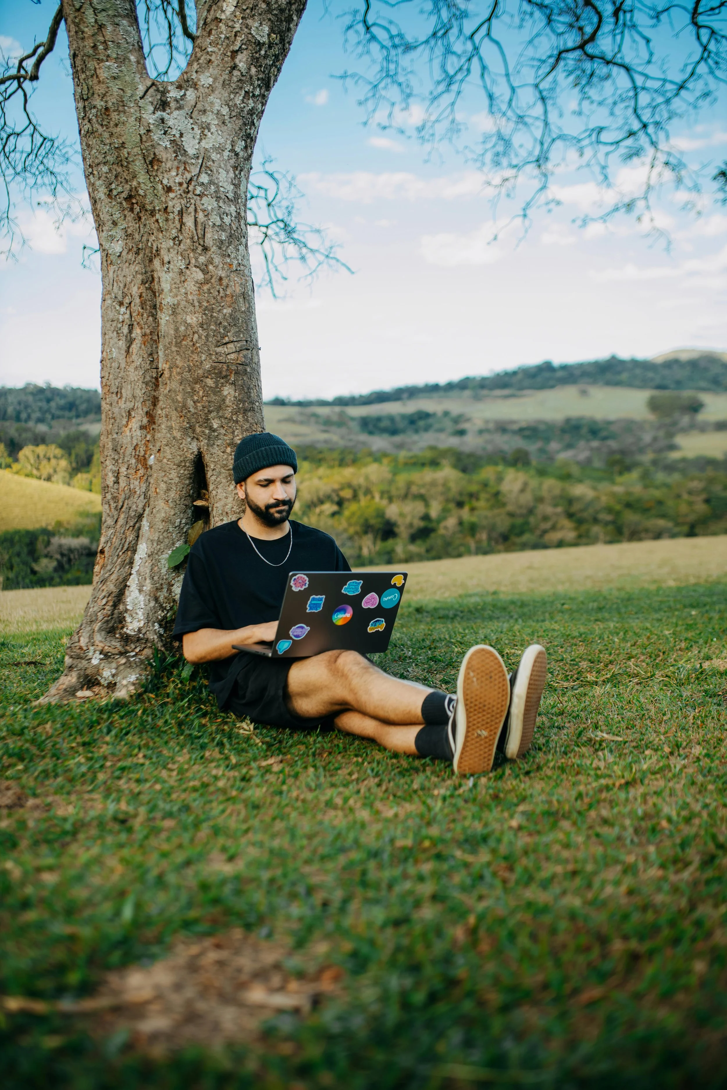 Man sitting against a tree with laptop