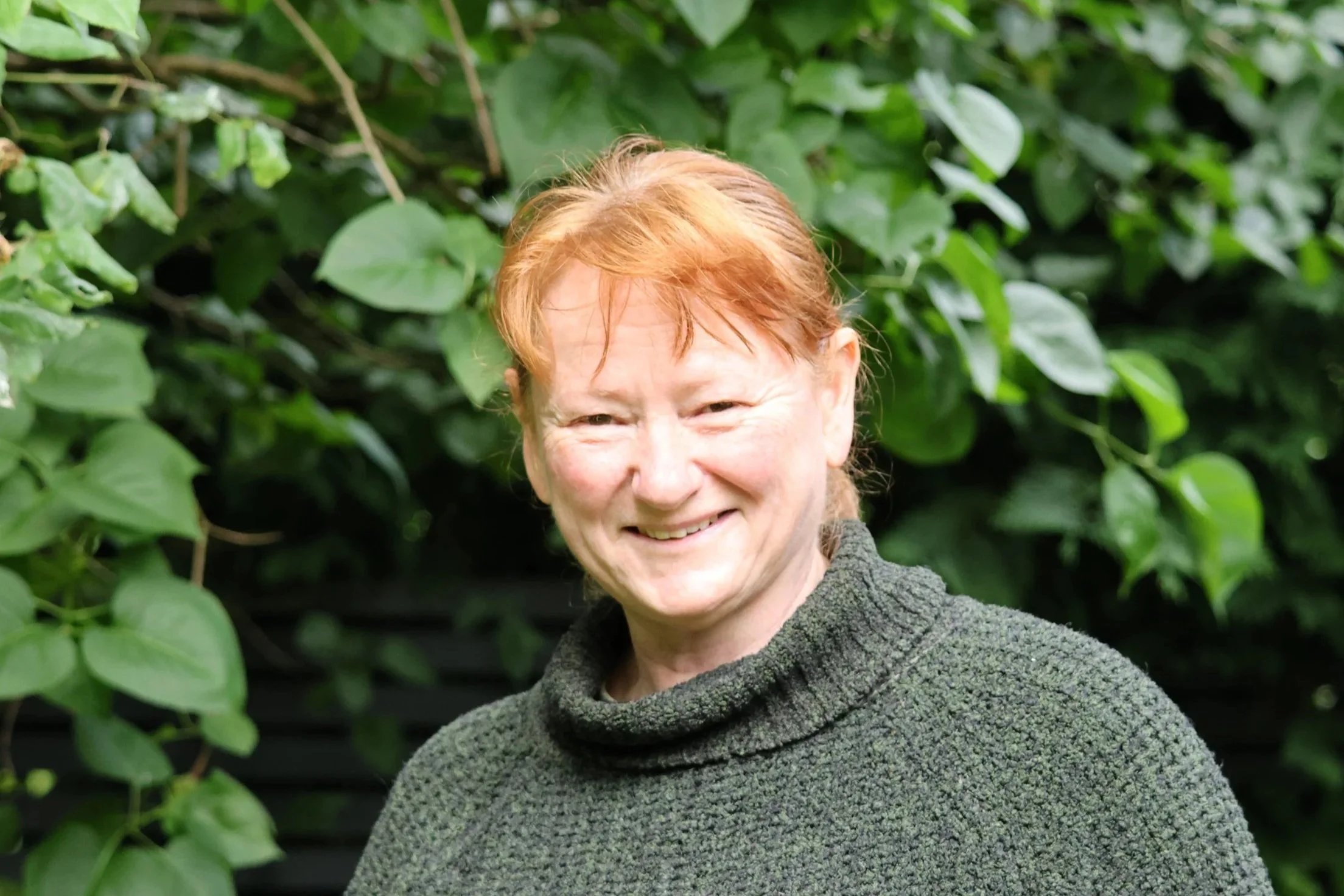 Jac Dennington portrait smiling against leafy backdrop
