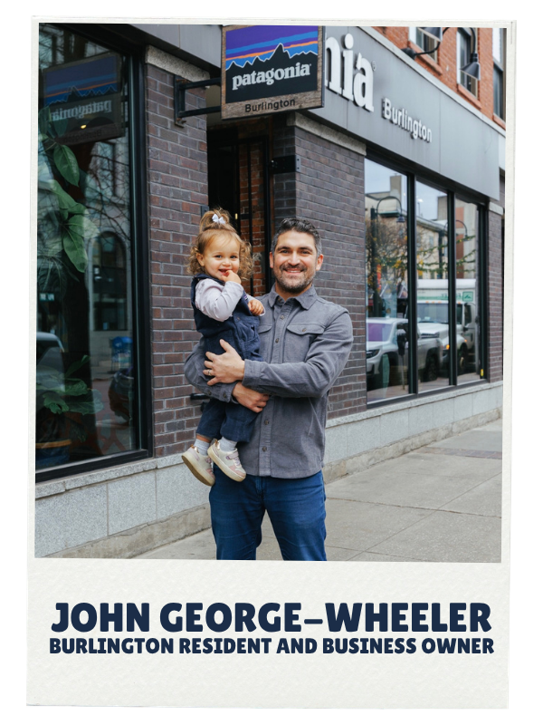 A man holding a young girl outside a merchandise store with a Patagonia sign, both smiling. The store is in Burlington.