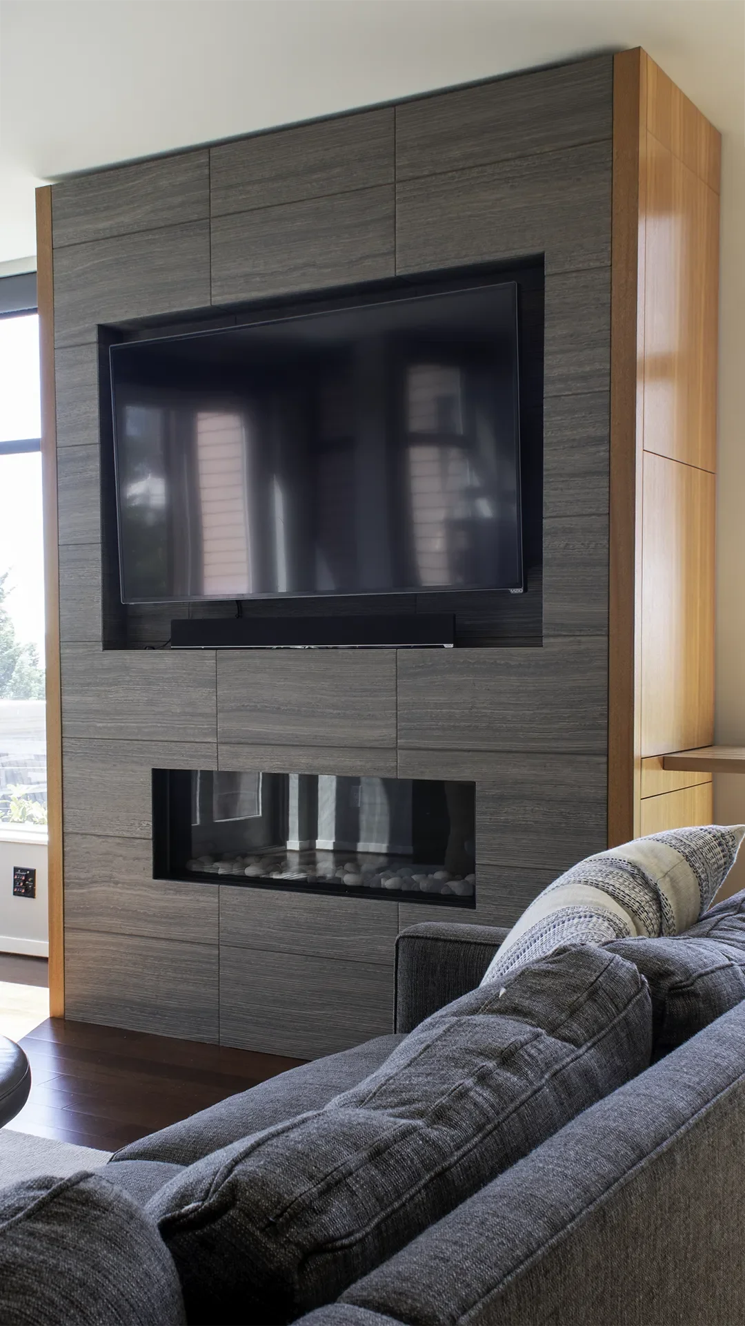 Seattle tile feature wall installation with gas fireplace, tile surround, custom, built-in storage with mahogany cabinets, and inset TV over fireplace.
