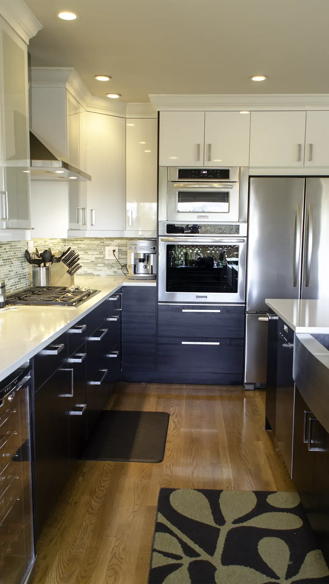IKEA kitchen installation in Seattle, featuring a combination of high-gloss white upper cabinets and dark woodgrain lower cabinets, green glass tile backsplash and white quartz countertops.