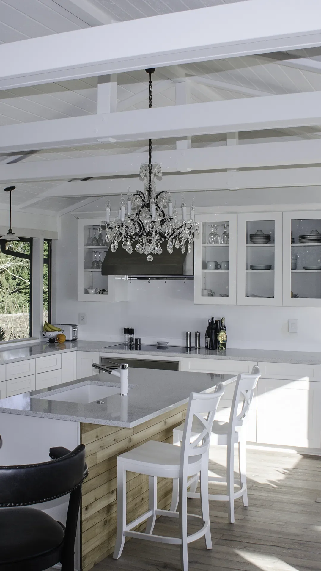 Seattle Modern Farmhouse style kitchen remodel, featuring white cabinets, shaker style cabinets, black, vintage style pendant lights and hardware, crystal chandelier over island and vaulted ceiling with whitewashed beams.