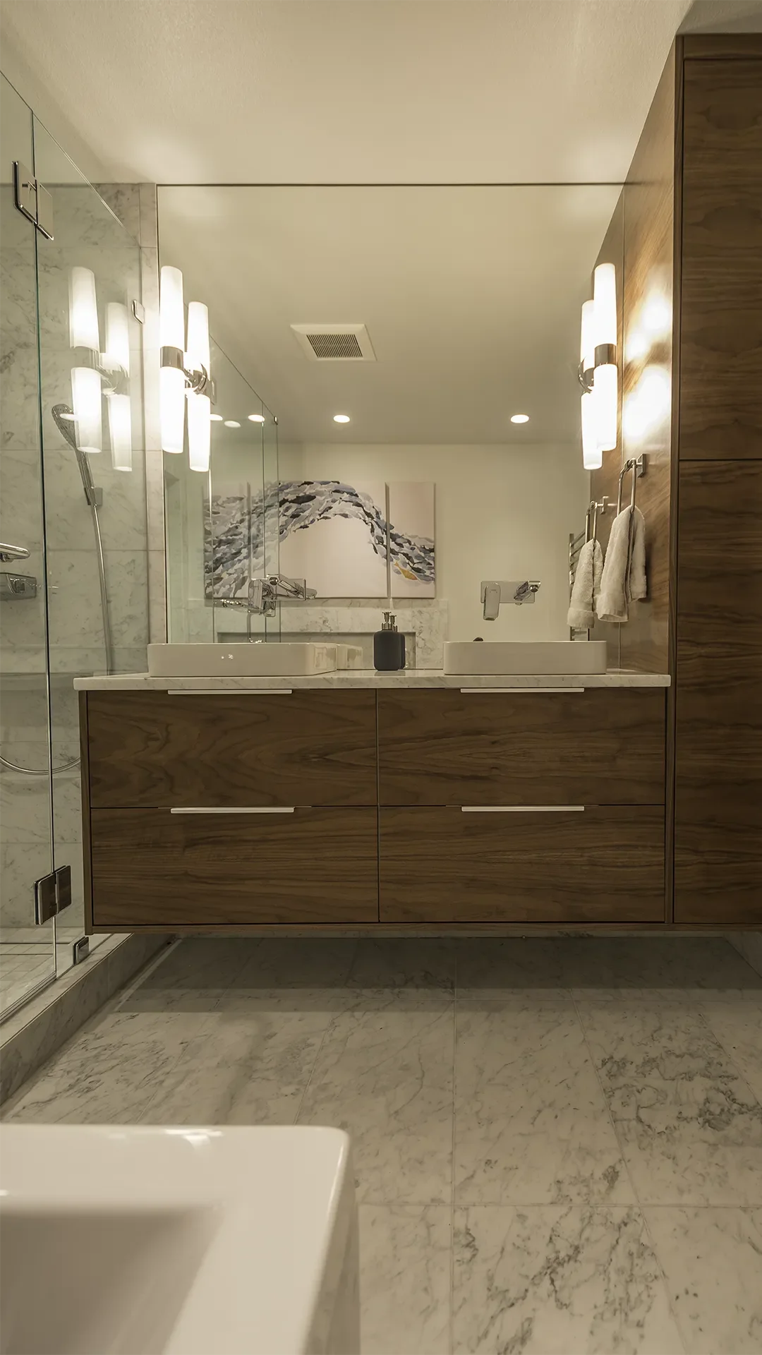 Gig Harbor bathroom remodel featuring a modern floating vanity with dual vessel sinks, wall-mounted chrome faucets, marble countertop, wall tile and flooring, and towel warmer.