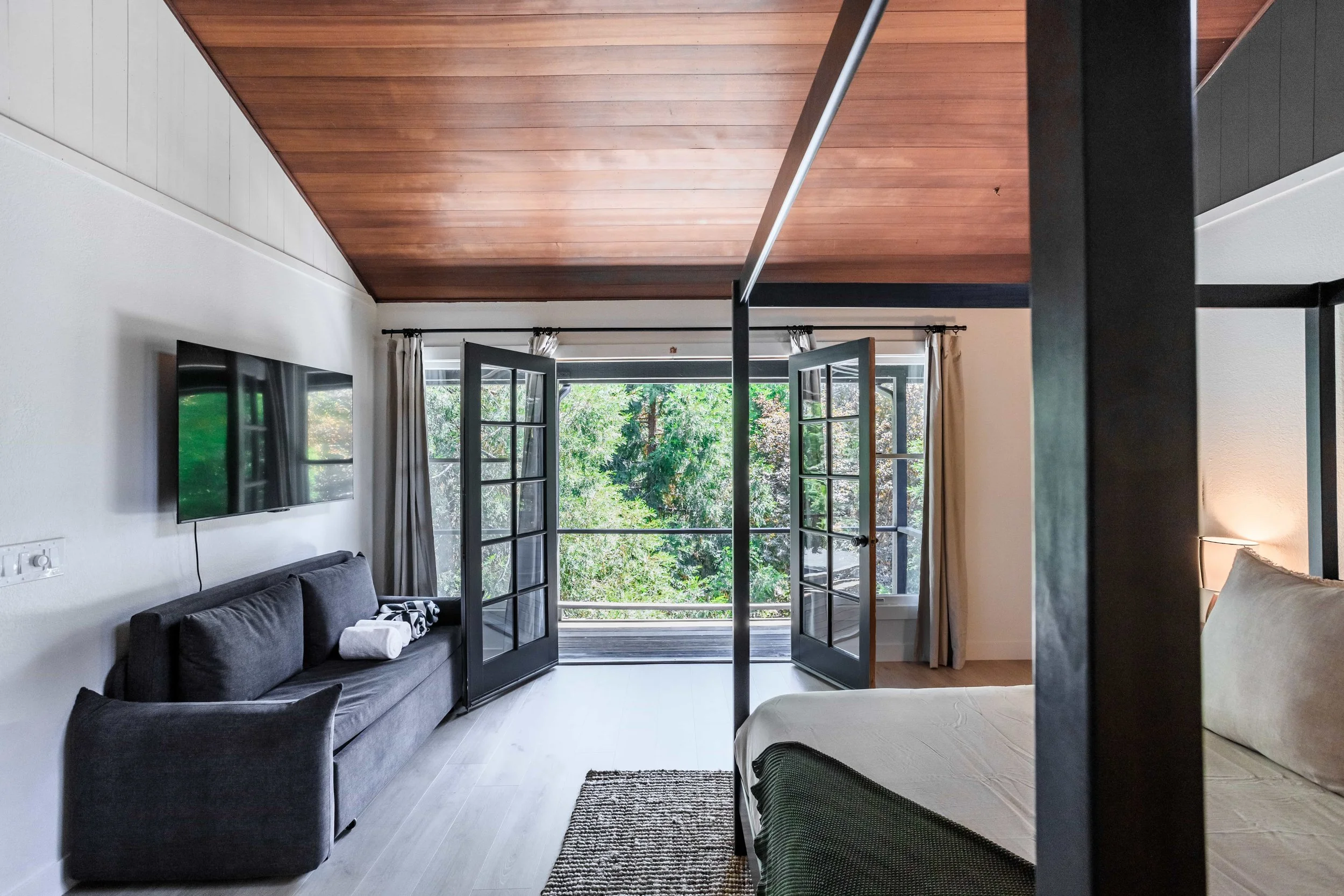 The Pinetree Hotel Idyllwild:  a - Idyllwild California, cozy cabin, mountain resort, mountain getaway Modern bathroom in cabin 1 with dark tiled walls, wooden ceiling, and walk-in shower with glass door and frosted window.