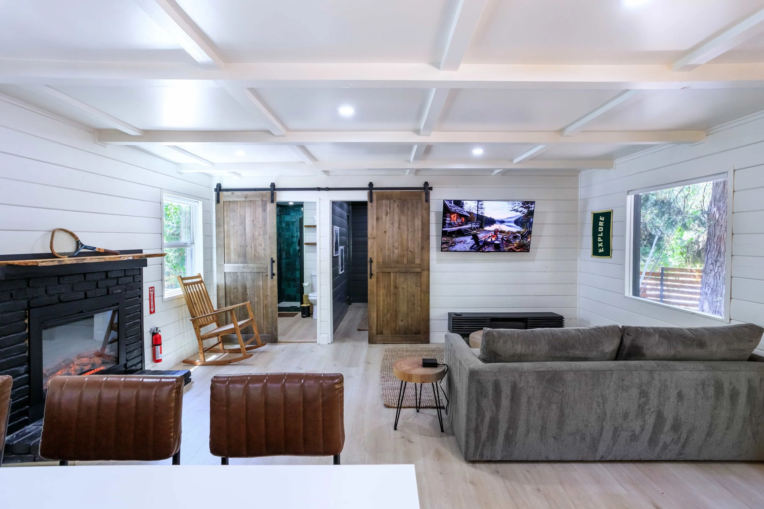 The Pinetree Hotel Idyllwild:  a - Idyllwild California, cozy cabin, mountain resort, mountain getaway Modern bathroom in cabin 1 with dark tiled walls, wooden ceiling, and walk-in shower with glass door and frosted window.