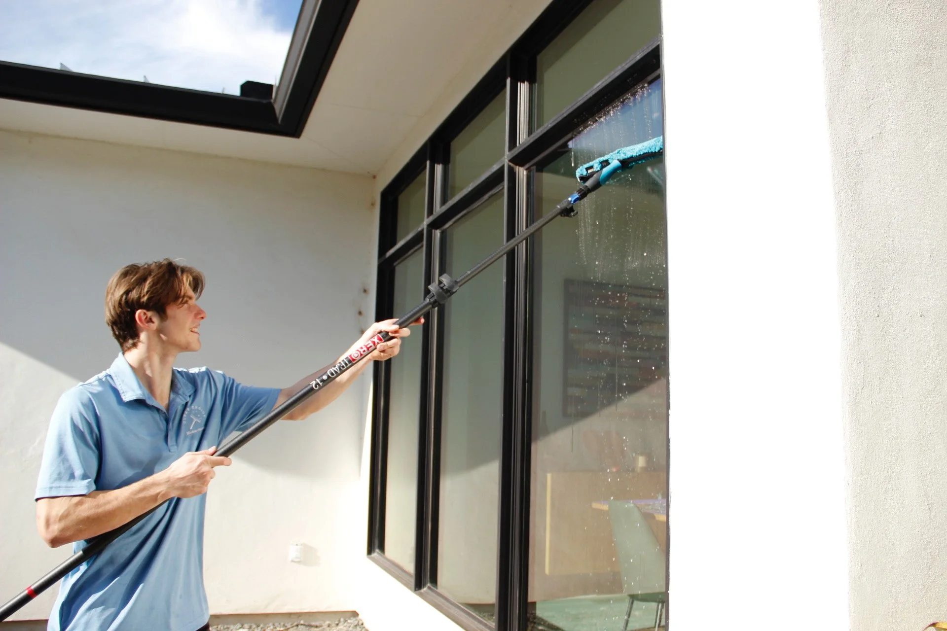 A person cleaning a large window with a squeegee outdoors.
