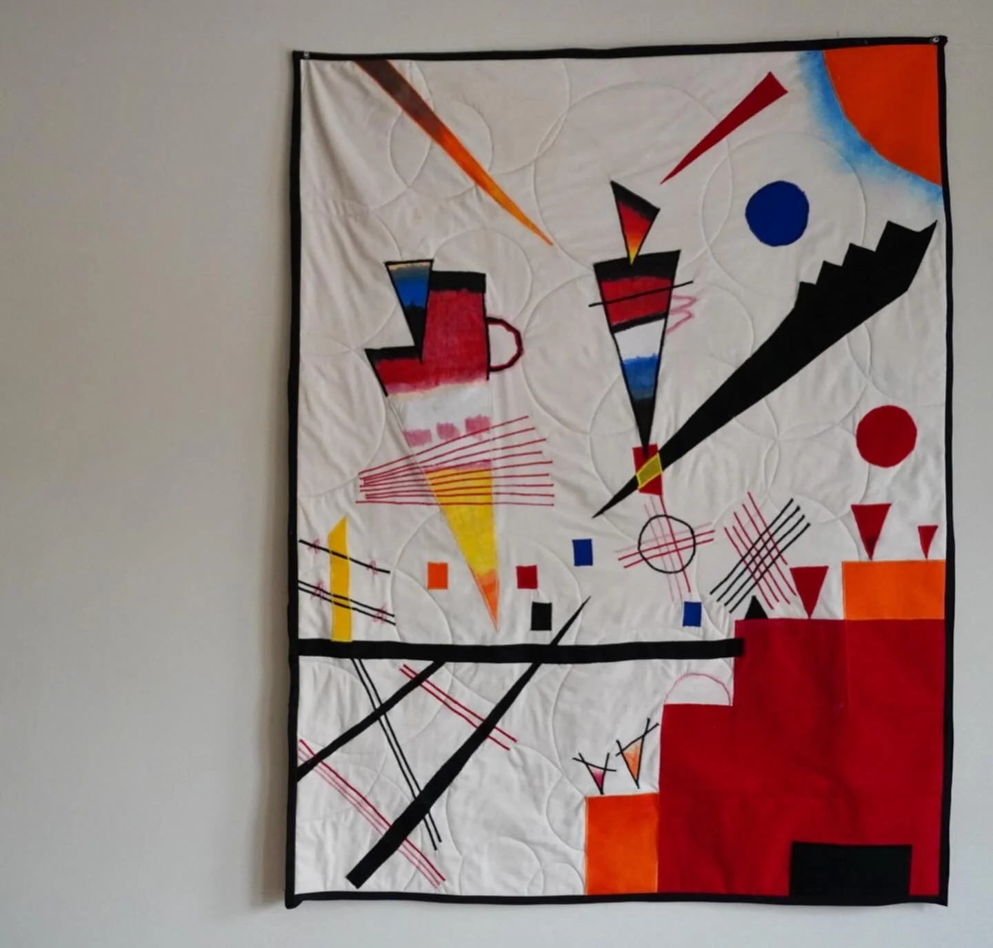Abstract art quilt with geometric shapes and bold colors including red, orange, yellow, blue, and black against a white background.
