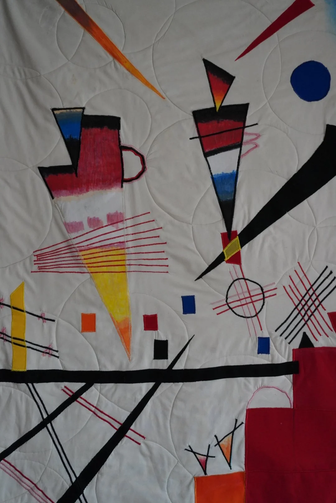 Colorful abstract geometric artwork on fabric with bold shapes, lines, and vibrant colors including red, yellow, blue, orange, and black.