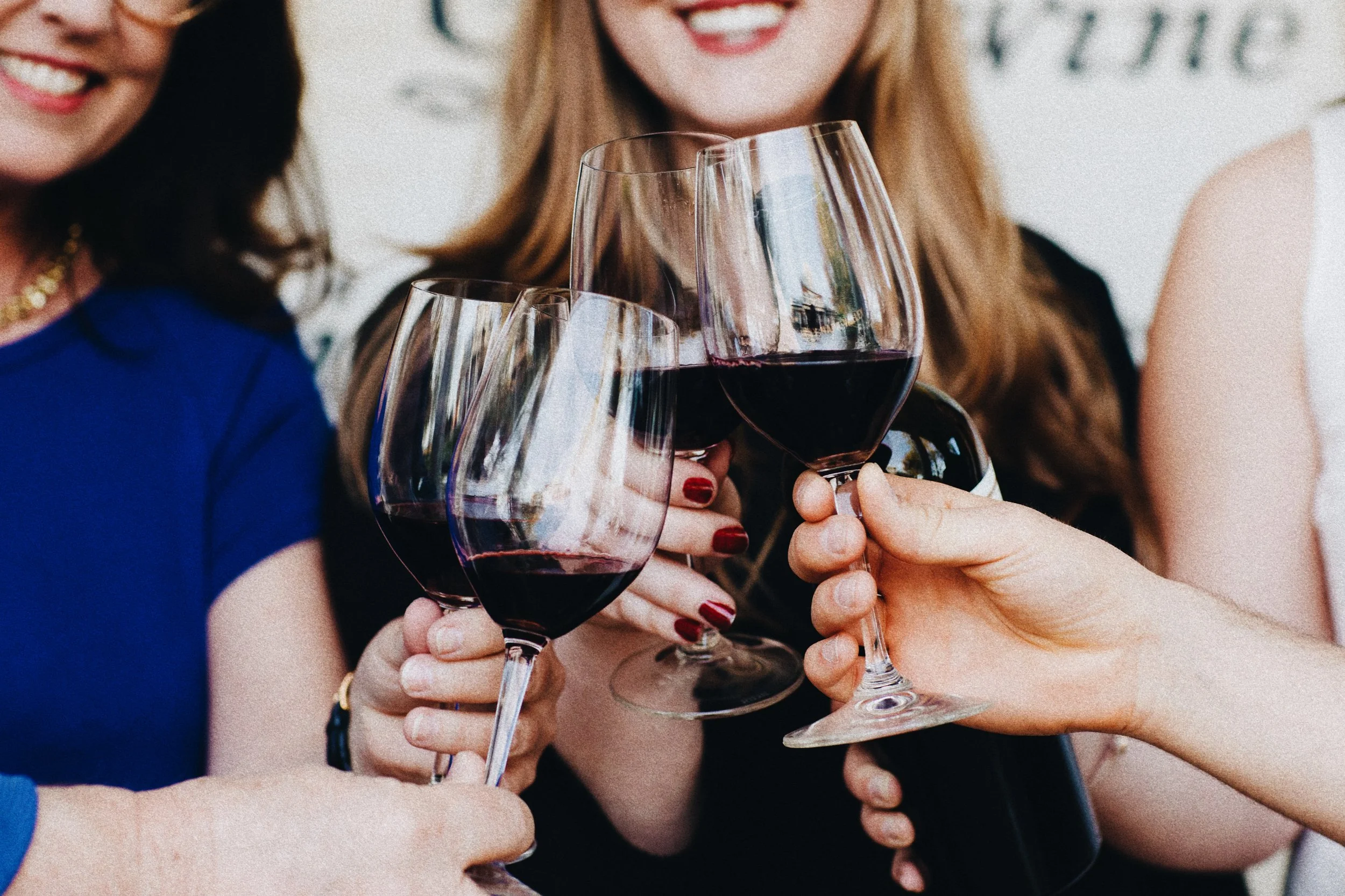 People clinking glasses of red wine in celebration.