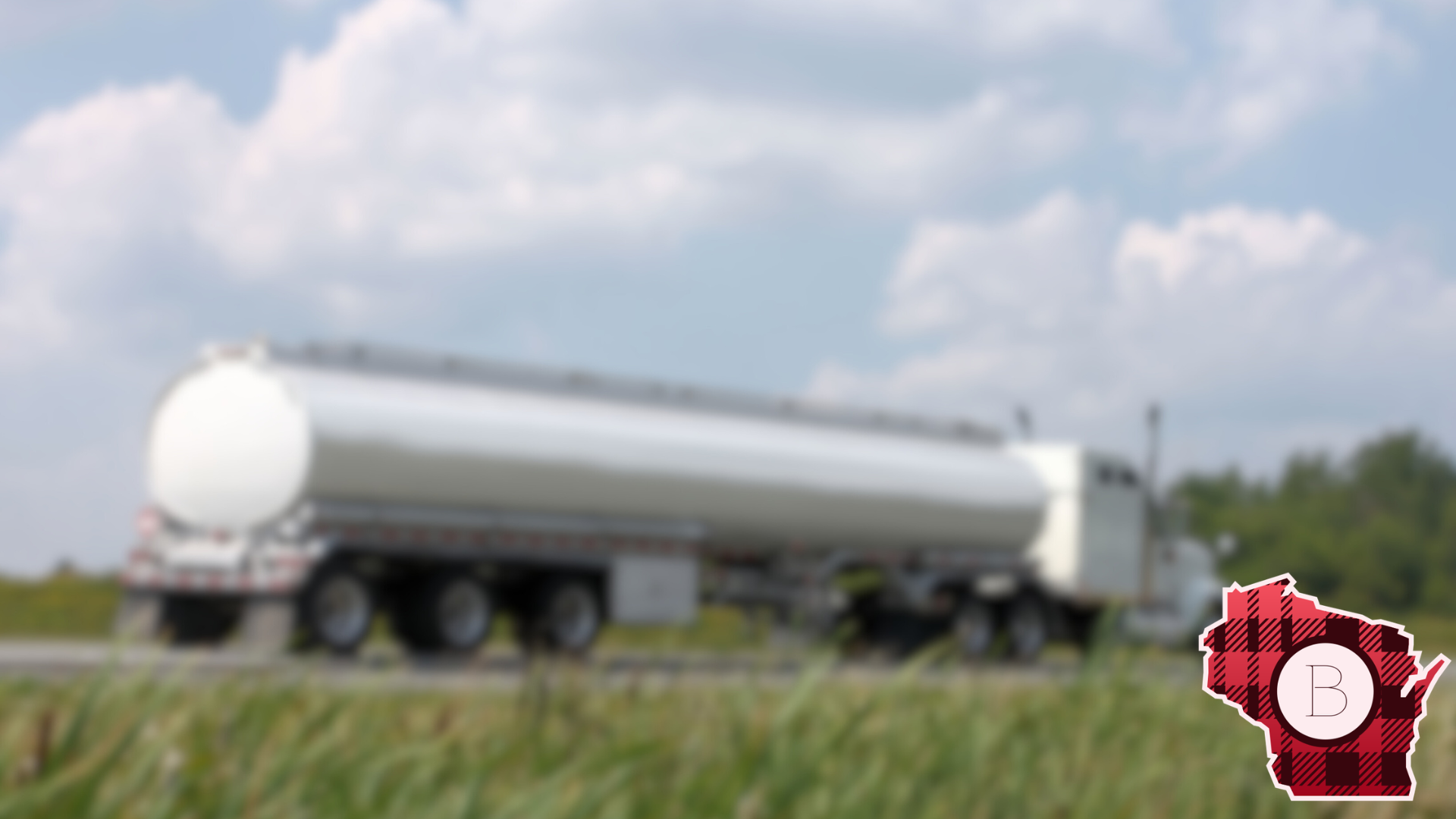 A blurry white tanker truck on a highway with a background of blue sky and clouds, and a red and black checkered outline of the state of Illinois with the letter B inside.