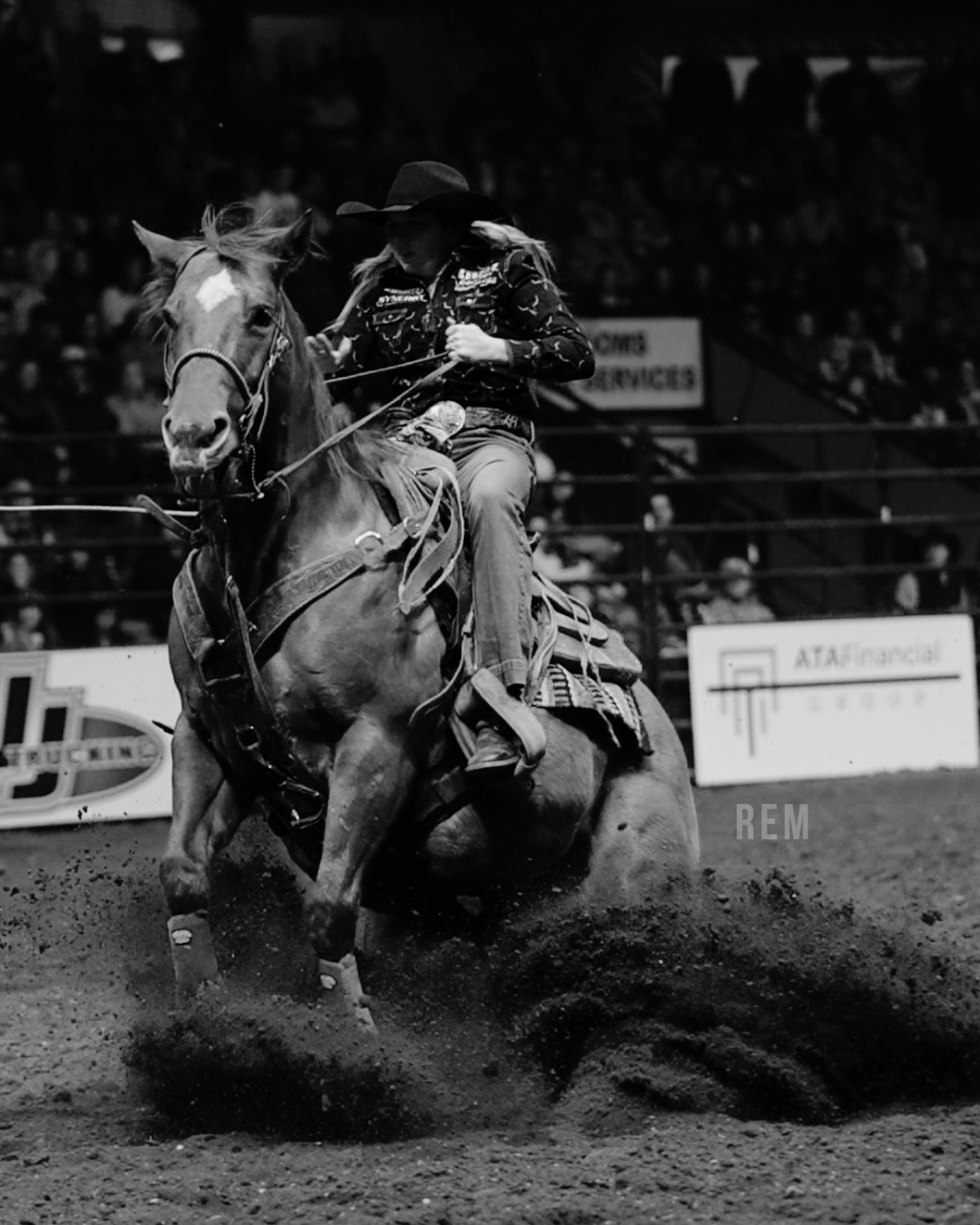 A Breakaway Roper riding a horse during a rodeo event at an indoor arena with spectators in the background.