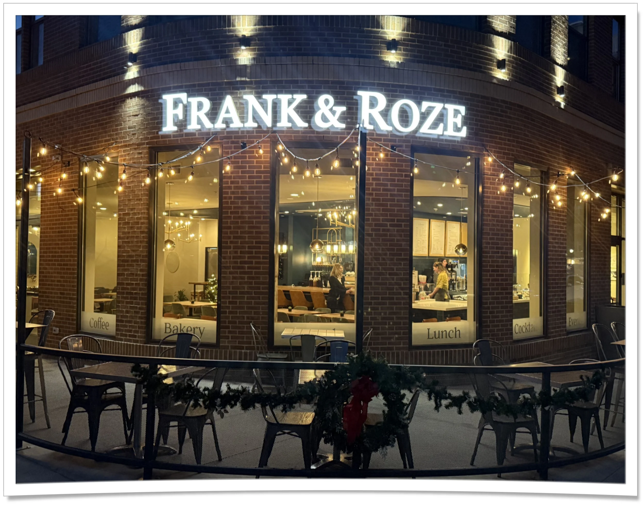 Exterior shot of Frank & Roze Uptown at night with string lights and red brick facade