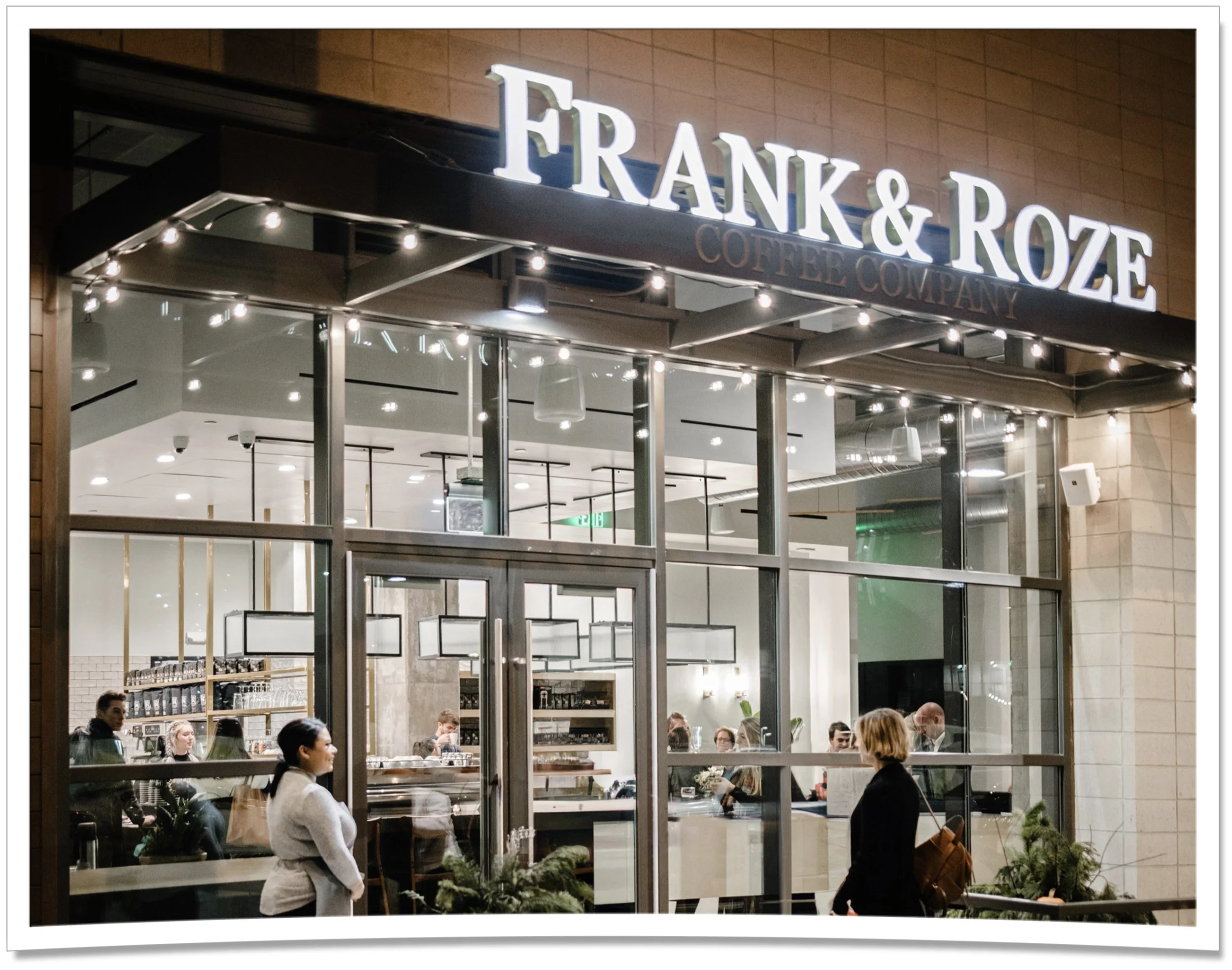exterior shot of Frank & Roze 9+CO at night with string lights, a modern facade and two people meeting outside