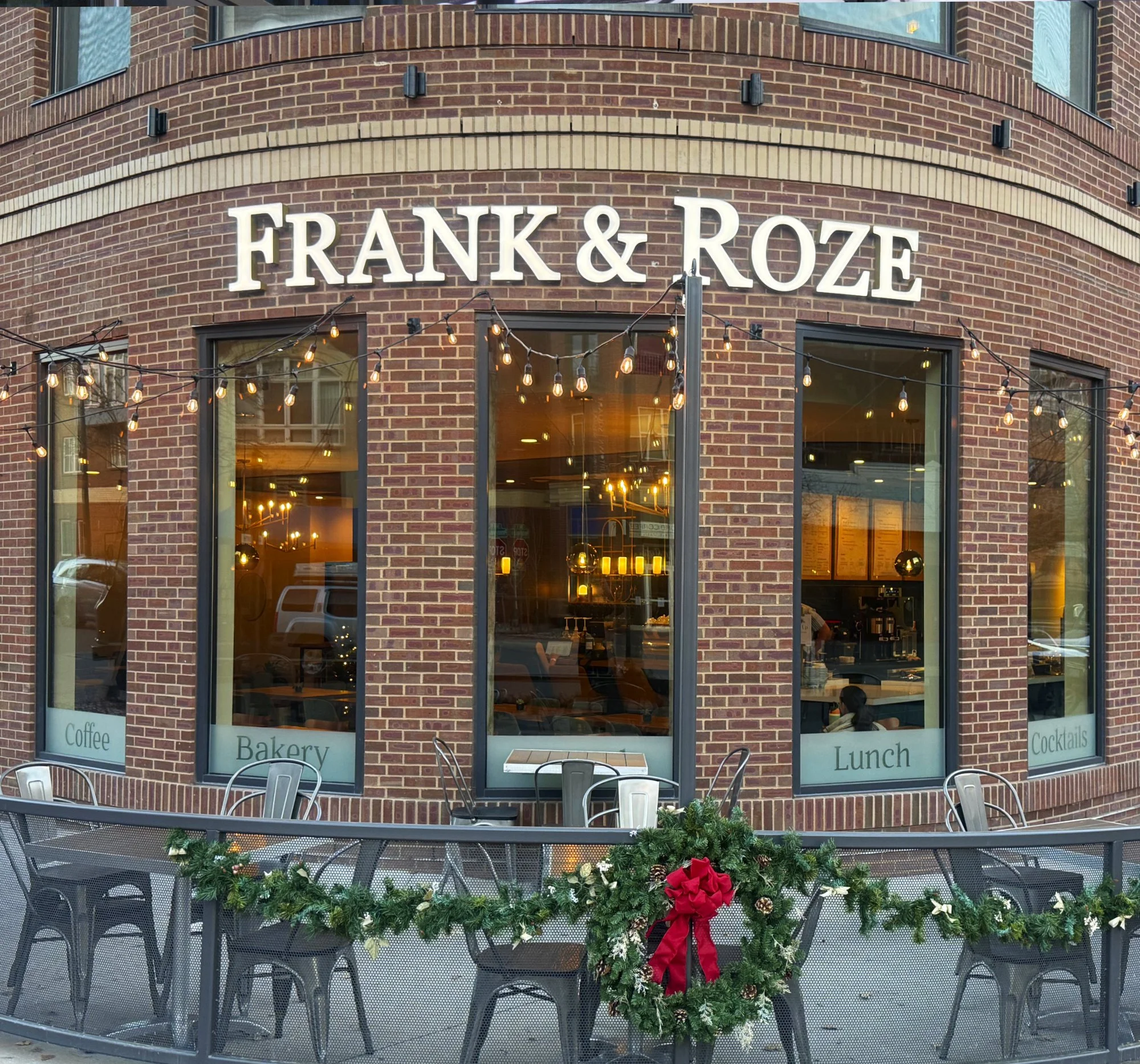 outdoor shot of the Frank & Roze sign on red brick building on a sunny winter day.  The corner of the building is a large rounded corner and the sign wraps around it