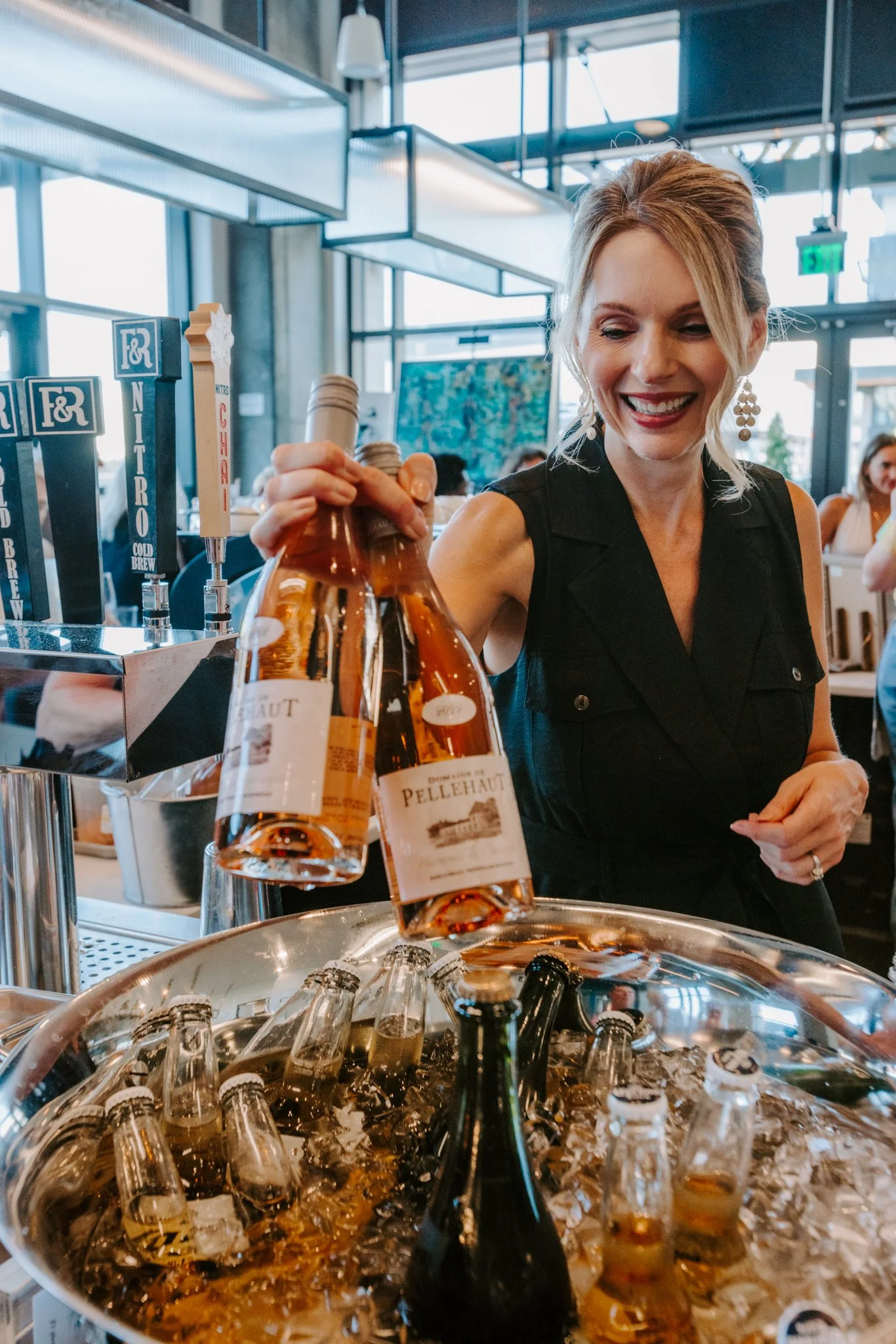 Brenda smiling as she pulls two bottles of rosé out of a large silver ice bucket