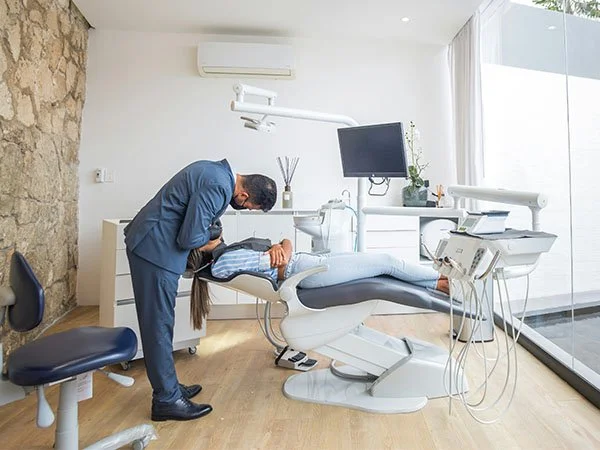 Dentist examining a patient lying in a dental chair in a modern dental office.