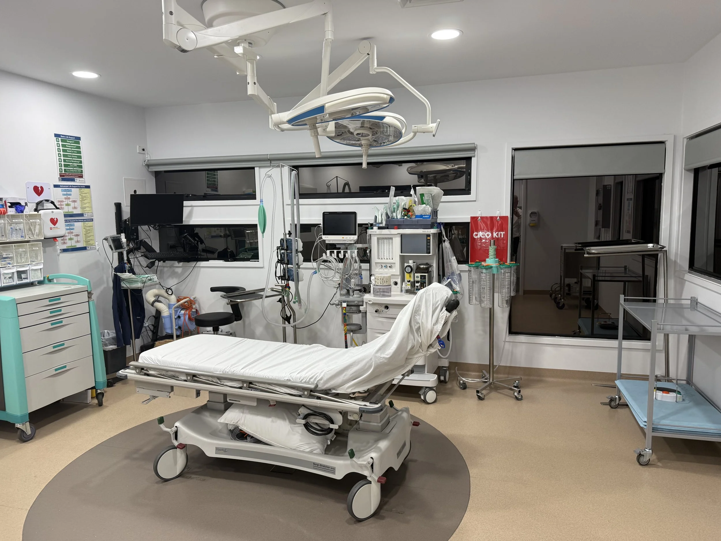 Empty hospital emergency room with hospital bed, medical equipment, monitors, and supplies.