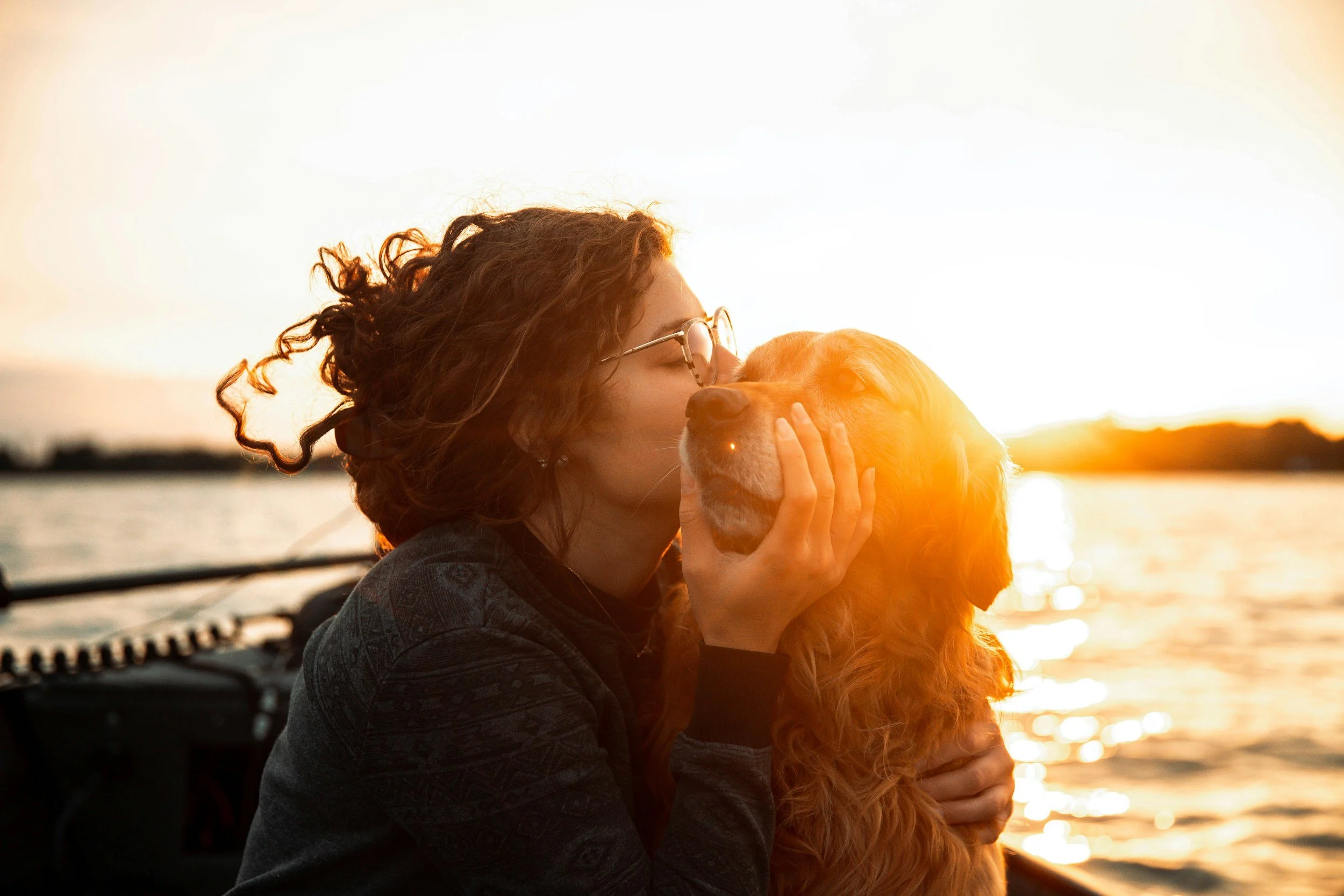 Woman kissing dog in front of water