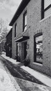 Black and white photo of a brick residential building with windows and a sidewalk with snow.