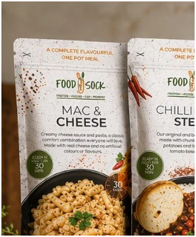 Two Food to Go soup packets, one labeled Mac & Cheese and the other Chili & Stew, with images of prepared dishes and ingredients on the packaging.