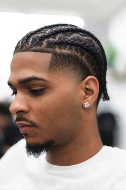 Cornrows:
Neatly braided cornrows that offer a stylish and protective look. This versatile style can be customized with different patterns and paired with a fade.