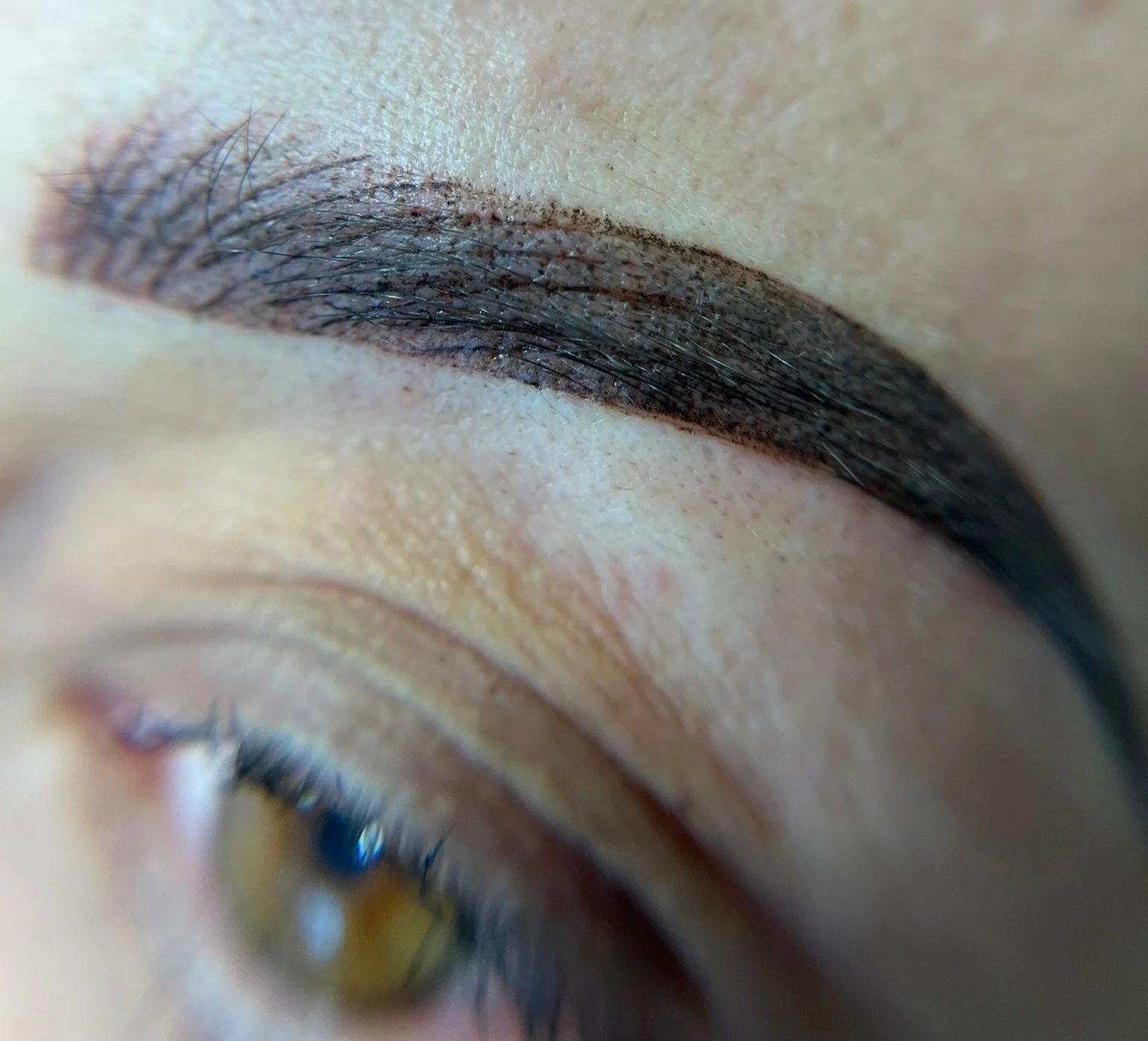 An extreme close-up of a person's closed eyelid with black eyeliner and mascara, showing detailed skin texture and eyelashes.
